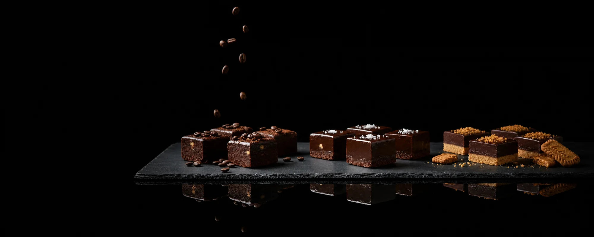 Alyoné fudge flavour assortment on black slate with a mirrored reflection